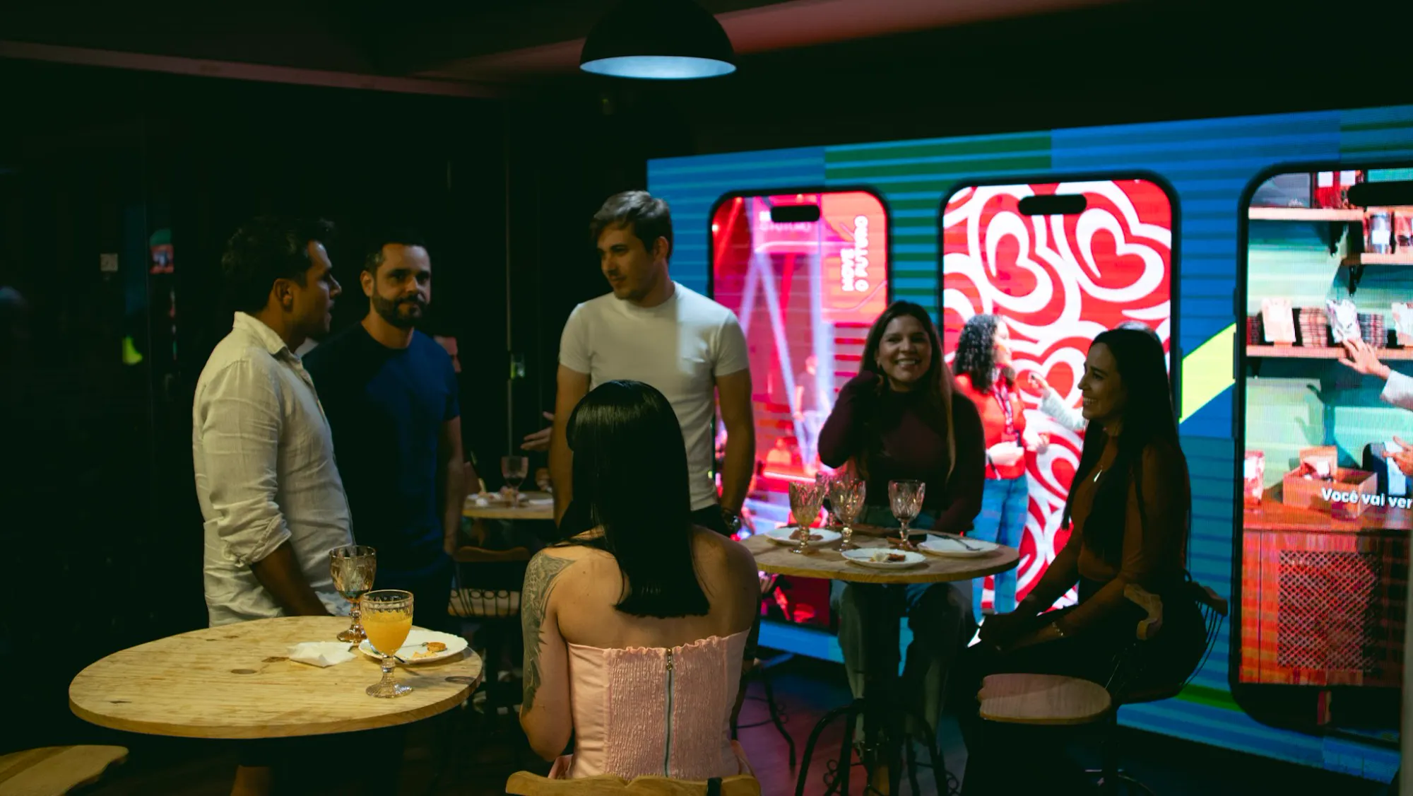Convidados em networking diante do painel de LED